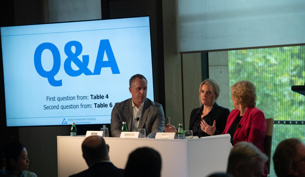 Panel discussion "Q&A" with three speakers engaging an audience in a conference room.