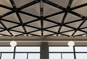 Geometric triangular acoustic ceiling panels with black framing and pendant globe lights in a modern event space with large windows.